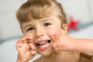 Cute little girl trying to floss- image from istockphoto