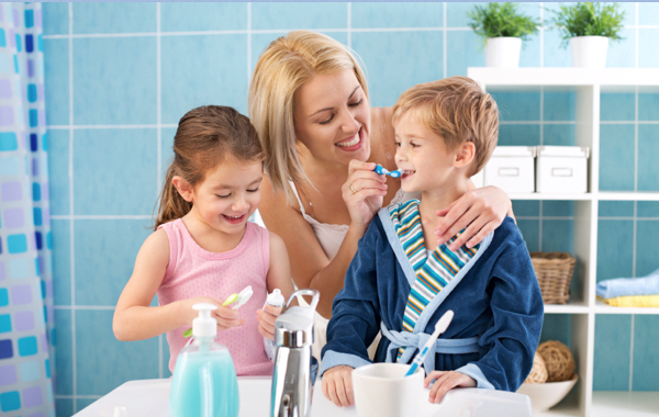 A mother helping her children to brush their teeth