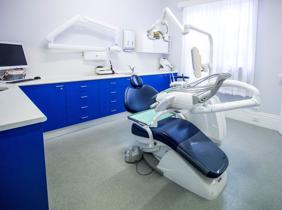 A dental treatment room in Ailin Teo Dental Surgery. It features a blue chair and various pieces of dental technology