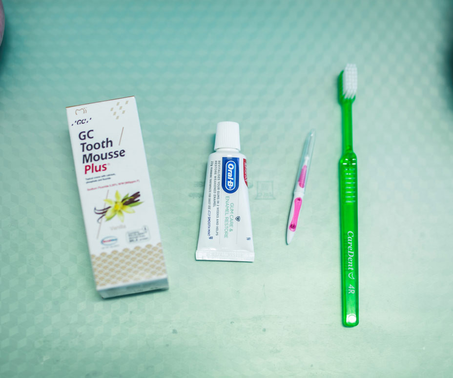 A pale green tray cover set up with items used for preventive dentistry, including Tooth Mousse, Toothpaste, interdental cleaner and green toothbrush.