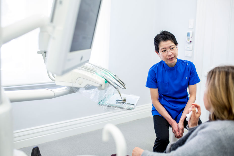 Dr Ailin Teo, Dentist, speaking to a patient in her treatment room