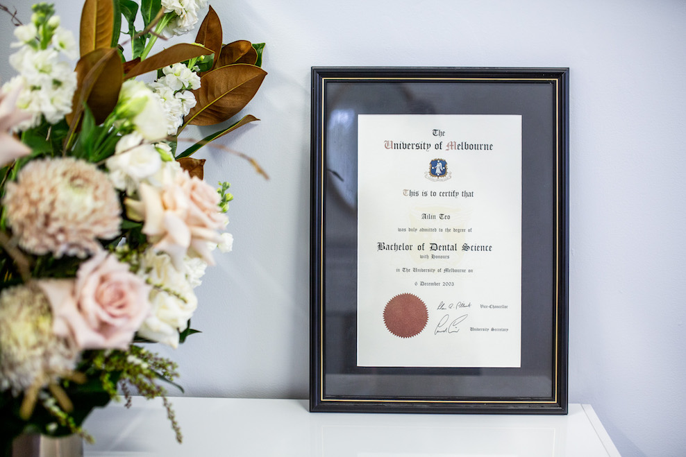 Dr Ailin Teo's framed Bachelor of Dental Science degree next to a vase of flowers